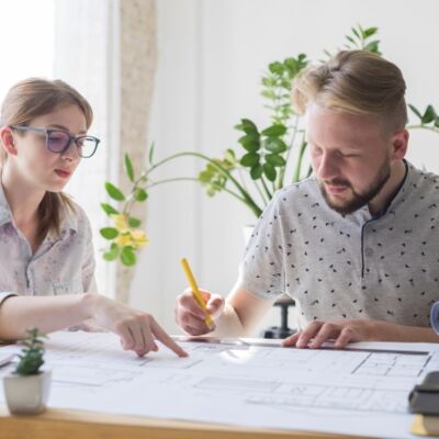 Deux personnes travaillent au plan d'un bâtiment